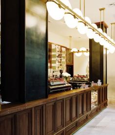 Portland, Oregon's Stumptown Coffee Roasters' west coast outpost is located in the trendy Ace Hotel's lobby. Roman and Williams decked out the walnut bar and enormous light with brass trimming, high-gloss painted wood shelves that are stacked with juicers and jars, and flooring got clad in travertine.