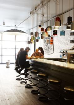 This cafe design is so neat! the corkscrew stools add so much visual insterest and soften up the lines to the space. The lighting is unique with its many different colors. The natural lighting entering into the space helps to brighten up the space. There are so many good design ideas to this space, its cool!