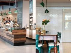 
                    
                        Market Lane Coffee - The casual seating area features a communal harvest table, accompanied by vintage Tolix chairs.
                    
                