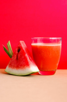 Watermelon Juice Filled Glass Cup Beside Sliced Watermelon Fruit on Brown Surface